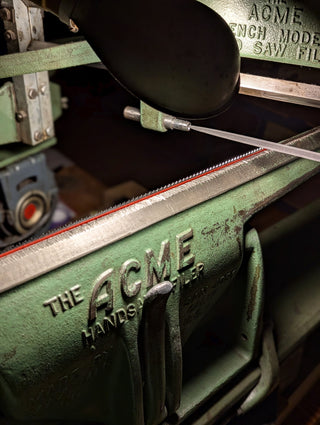 an acme handsaw filer sharpening a saw